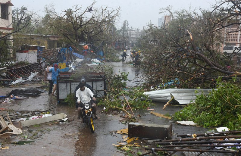 People move through debris on a road May 3