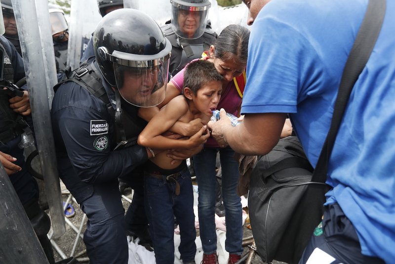 A young boy heading to the United States with other migrants from Central America is given water by Guatemalan police Dec. 19. On Dec. 24