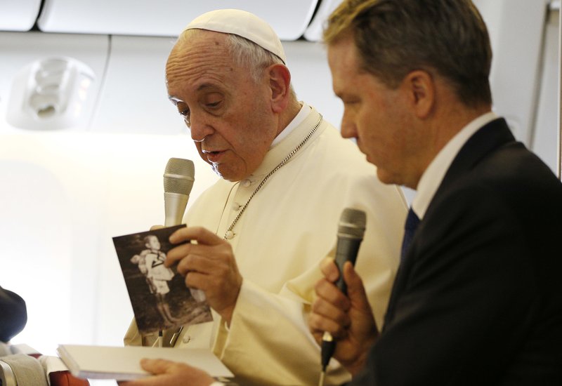 Pope Francis holds a card with a 1945 photo from the aftermath of the atomic bombing of Nagasaki