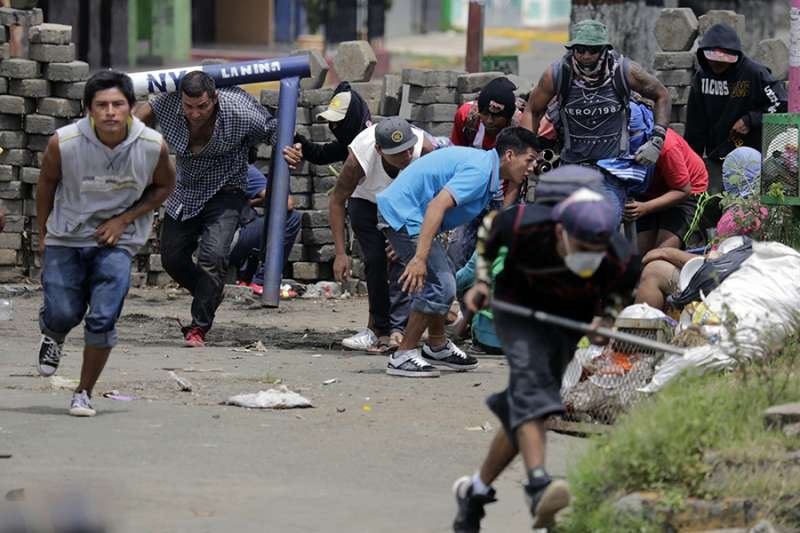 Anti-government demonstrators take cover behind a barricade