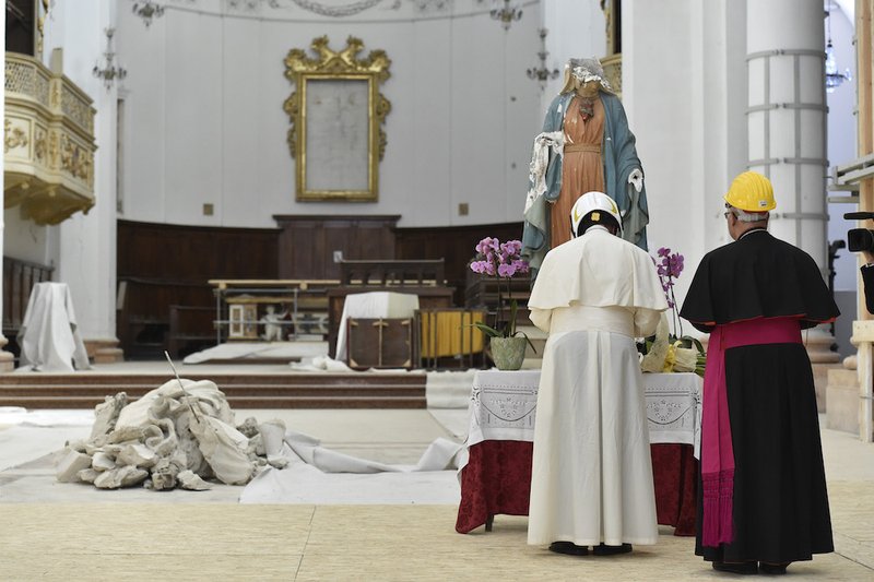 Pope Francis and Archbishop Francesco Massara of Camerino-San Severino Marche pray before a partially destroyed statue of Mary in the cathedral of Camerino