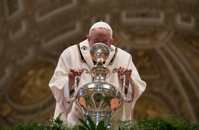 Pope Francis blows inside an amphora containing holy oil during a Chrism Mass inside St. Peter's Basilica