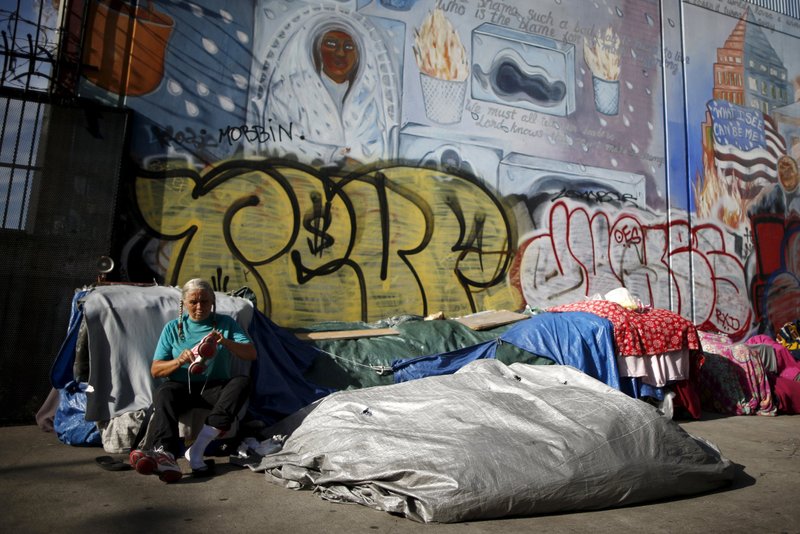 A woman sits outside her tent on Skid Row in downtown Los Angeles Oct. 1