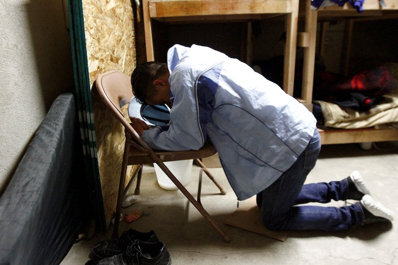 A Honduran migrant prays at a shelter in Tijuana