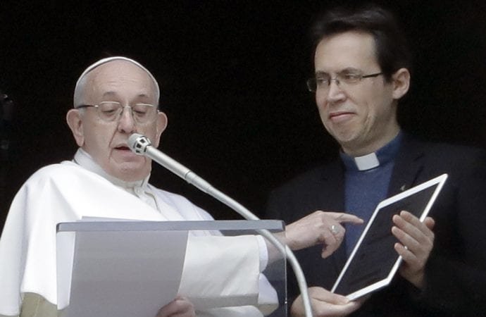 Pope Francis points at a tablet as he unveils his own user profile in Click To Pray