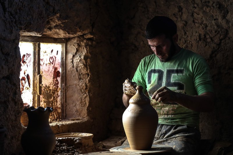 A Syrian man works on a clay pot in early July at a traditional pottery workshop in Idlib. (CNS photo/Mohammed Badra