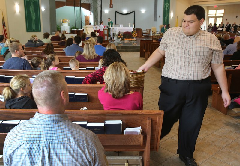 An usher hands the collection basket to a Massgoer Oct. 28