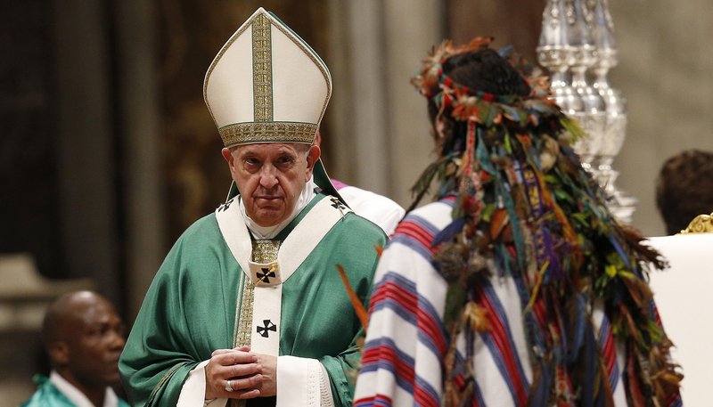 Pope Francis accepts offertory gifts from an indigenous man as he celebrates the concluding Mass of the Synod of Bishops for the Amazon at the Vatican Oct. 27, 2019. (CNS photo/Paul Haring)