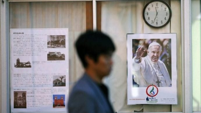 In this Nov. 16, 2019, photo, a man walks by a poster of Pope Francis at the Urakami Cathedral in Nagasaki, southern Japan. Pope Francis will start his first official visit to Japan in Nagasaki, ground zero for the Christian experience in a nation where the Catholic leader once dreamed of living as a missionary. (Eugene Hoshiko/AP via Crux)