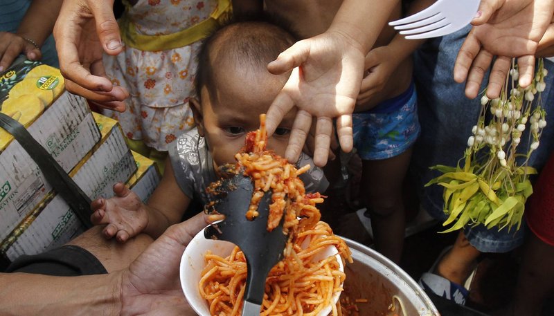 Children receive free meals Jan. 4, 2013, in front of a Catholic church in Manila, Philippines. Catholic leaders in the Philippines have appealed to churchgoers to bring gifts for the poor when they attend Mass, especially during the observance of World Day of the Poor Nov. 17, 2019. (CNS photo/Romeo Ranoco, Reuters)