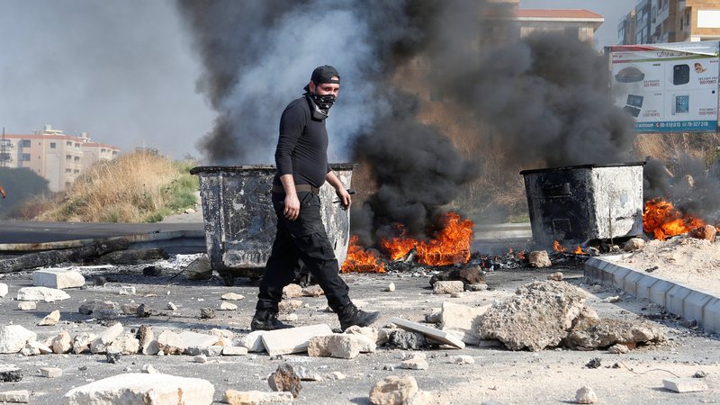 A demonstrator walks near burning tires barricading a road during ongoing anti-government protests in Khaldeh, Lebanon, Nov. 13, 2019. (CNS photo/Mohamed Azakir, Reuters)