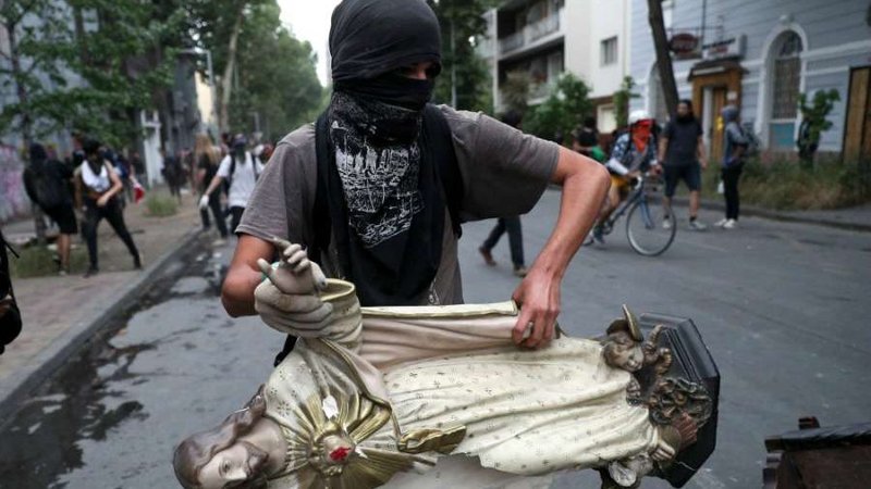 A protester carries a statue of Christ from La Asuncion church to be added to a barricade in Santiago, Chile, Nov 8, 2019. (Esteban Felix/AP/Shutterstock via CNA. Not licensed for redistribution)