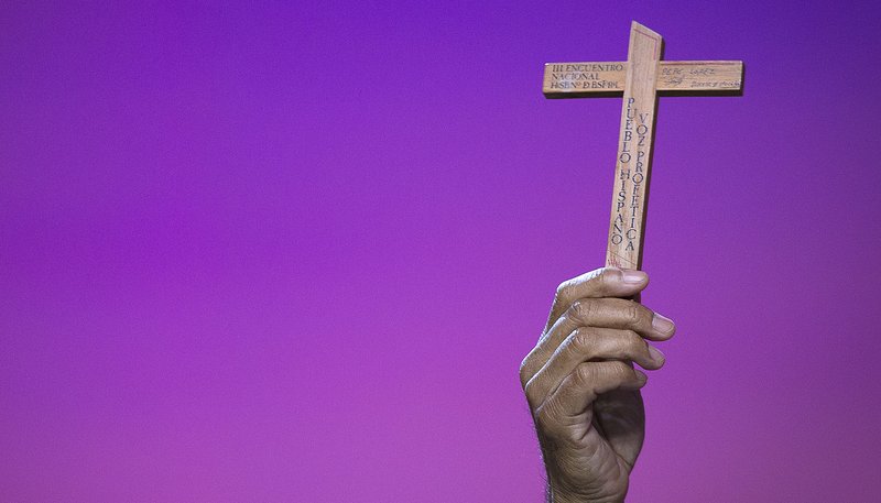 Jose Lopez, Hispanic minister from Stockton, Calif., raises the cross he received in 1985 from the Third National Encuentro during a Sept. 22 plenary session at the V Encuentro in Grapevine, Texas. (CNS photo/Tyler Orsburn)
