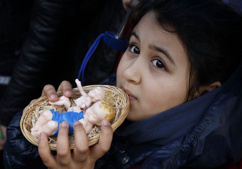 A girl holds baby Jesus figurines for Pope Francis to bless during his Angelus delivered from the window of his studio overlooking St. Peter's Square at the Vatican Dec. 15, 2013. While the days leading to Christmas are filled with shopping and other holiday preparations, the pope recommended that people also find time for silence so they can listen to God. (CNS photo/Paul Haring)