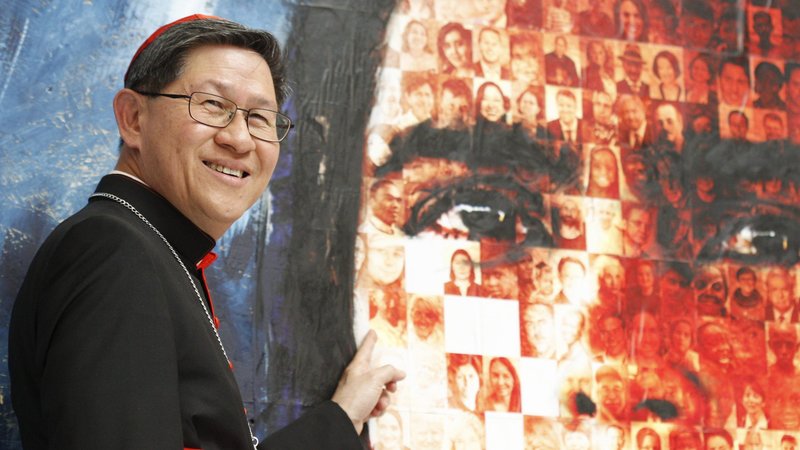 Philippine Cardinal Luis Antonio Tagle of Manila points to a photo of his maternal grandfather, who emigrated from China to the Philippines. During a Vatican news conference May 23, the cardinal added the photo of his "Lolo Kim" to the mosaic made of the faces of migrants, world leaders and Caritas staff members from around the world. (CNS photo/Robert Duncan)