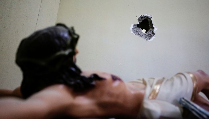 A bullet hole in the town hall of Villa Union, Mexico, is seen near a sculpture of Jesus Dec. 2, 2019. To the south, the Diocese of Cuernavaca has suspended evening Masses due to insecurity in the city and surrounding state of Morelos, a reflection of the violence raging in parts of Mexico and its impact on the Catholic Church. (CNS photo/Daniel Becerril, Reuters)