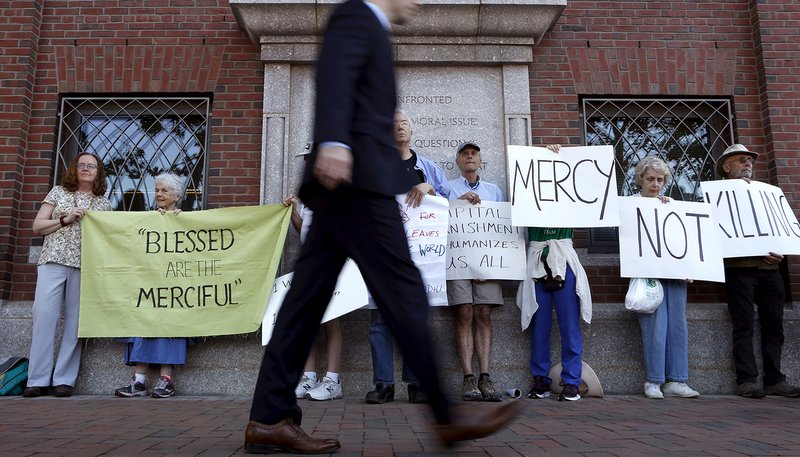 A pedestrian walks past death penalty protesters before the formal sentencing of convicted Boston Marathon bomber Dzhokhar Tsarnaev at the federal courthouse in Boston June 24, 2015. Use of the death penalty in the United States continues to decrease, according to a report released Dec. 17, 2019, by the Death Penalty Information Center. (CNS photo/Dominick Reuter)