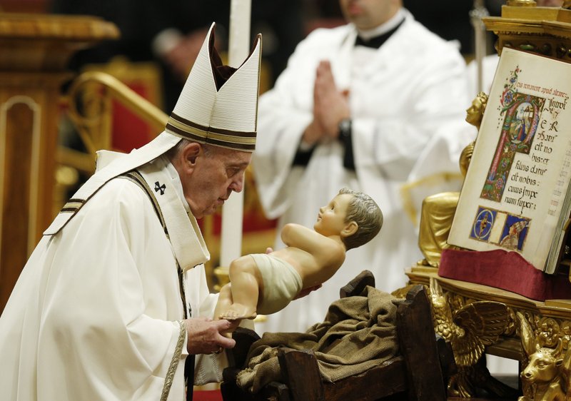 Pope Francis picks up a figurine of the baby Jesus to carry in procession at the conclusion of Christmas Mass in St. Peter's Basilica at the Vatican Dec. 24, 2019. (CNS photo/Paul Haring)
