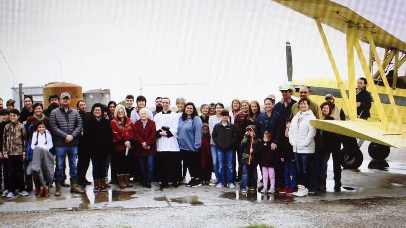 Parishioners of St. Anne Church in Cow Island, La., stand next to the crop duster that had 100 gallons of holy water on it to bless the nearby farms and town. (CNS photo/social media, Diocese of Lafayette)