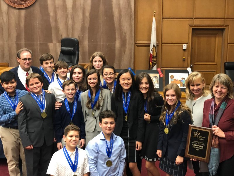 From left: Judge Randolph Hammock. Team members Graham Nevell, Max Shaffer, Amelia Tran, Mario Vega, Caleb Kona, Sammy Riechmann, Natalia Conzalez, Charlies Caruso, Carissa Klaus, Jude Filippone, Hartley Decauwer, Carolyn Freese, Emily Mota, and Emma Mendoza-Munoz, with coaches Diane Evans and Tracey Merritt. (Courtesy Holy Family Catholic School)