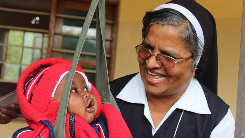 Sister Rashmi Mattappally plays with a child while taking his weight at a local dispensary in Loiborsiret, Tanzania. (CNS photo/Doreen Ajiambo, Global Sisters Report)