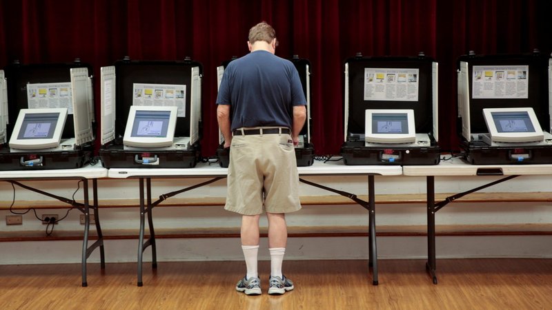 A man casts his vote in 2017 at Holy Cross Catholic Church in Tucker, Ga. In some parts of the U.S., regular Massgoers have been tracked through cellphone location data by at least one organization looking to turn out voters to support specific political candidates. (CNS photo/Chris Aluka Berry, Reuters)