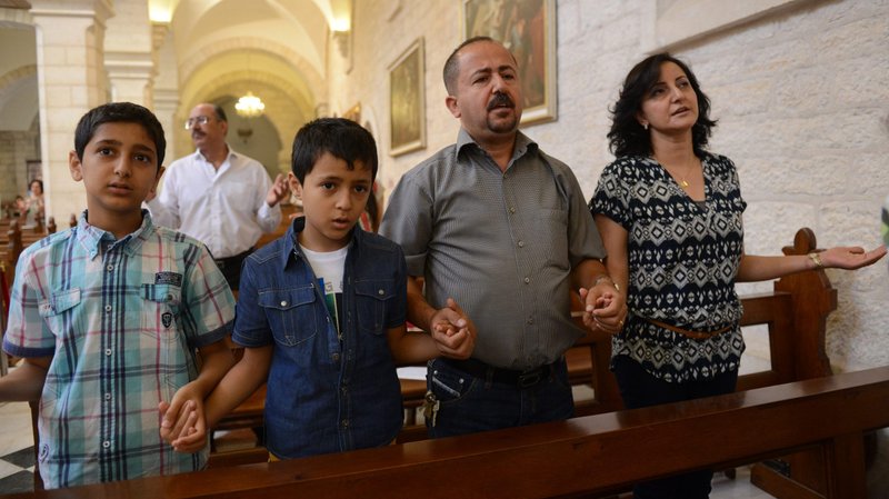 A family prays during Mass in the Church of St. Catherine in Bethlehem, West Bank. (CNS photo/Debbie Hill)