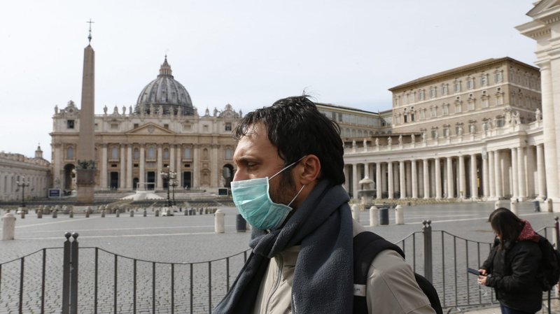 A man wearing a mask for protection from the coronavirus passes an empty St. Peter's Square at the Vatican March 10, 2020. The Vatican has closed St. Peter's Square and Basilica to tourists March 10 through April 3 in cooperation with Italian emergency procedures aimed at preventing the spread of the coronavirus. (CNS photo/Paul Haring)