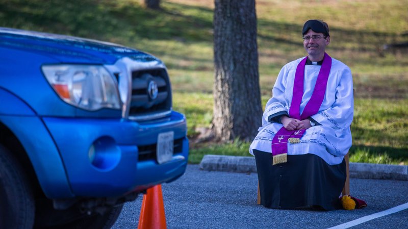 Father Scott Holmer, pastor at St. Edward the Confessor Catholic Church in Bowie, Md., offers drive-through confessions in the parking lot of the parish March 18, 2020, keeping a safe distance away from penitents amid the coronavirus pandemic. (CNS photo/Andrew Biraj, Catholic Standard)