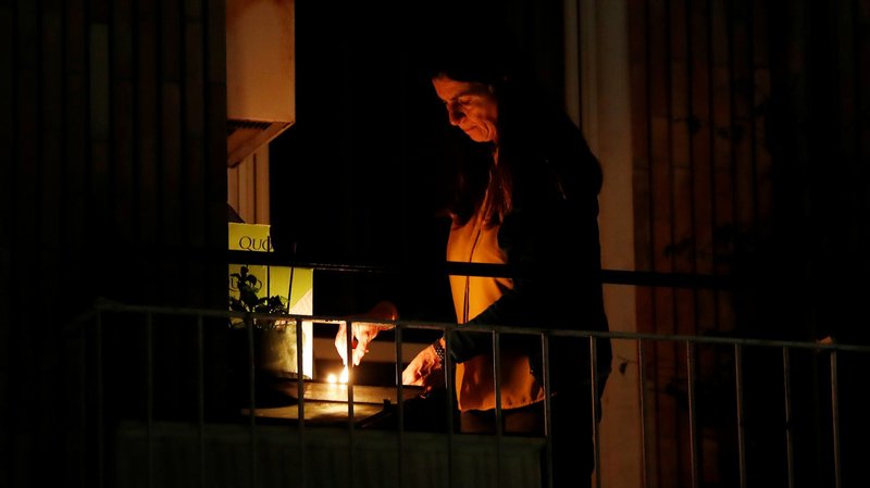 A woman lights a candle on her balcony in Rome March 19, 2020, as faithful across Italy say a prayer for people suffering from COVID-19. (CNS photo/Yara Nardi, Reuters)