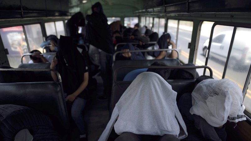 Guatemalan migrants cover themselves while on a bus outside La Aurora International Airport in Guatemala City, Guatemala, March 19, 2020, after being deported from the U.S. Catholic immigration advocates are calling for immigrant protections amid the coronavirus (COVID-19) pandemic. (CNS photo/Fabricio Alonso, Reuters)