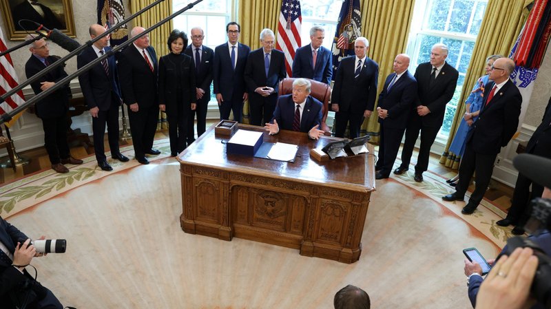 President Donald Trump signs the $2.2 trillion coronavirus aid package bill in the Oval Office of the White House March 27, 2020. Archbishop Paul S. Coakley of Oklahoma City, chairman of the U.S. bishops' Committee on Domestic Justice and Human Development, praised members of Congress and the president March 28 for passing and signing into law the Coronavirus Aid, Relief and Economic Security Act. (CNS photo/Jonathan Ernst, Reuters)