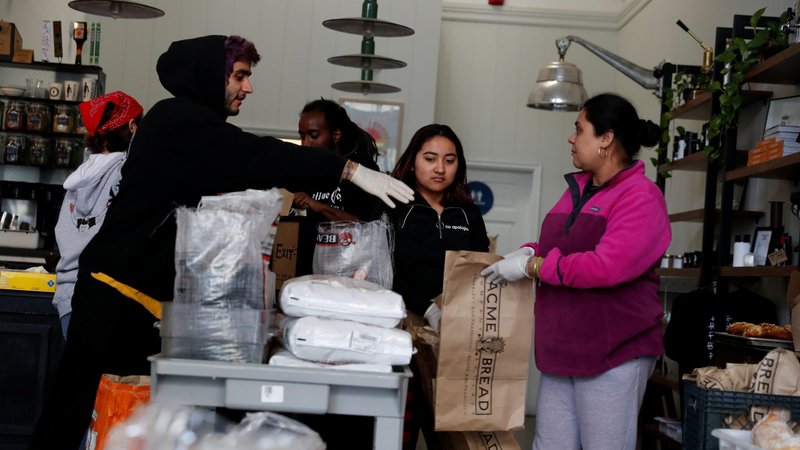 Employees laid off from an Oakland, Calif., cafe that closed due to the financial crisis caused by the coronavirus collect food items March 18, 2020. Dozens of institutional investors, including Catholic religious congregations, labor unions, public pensions and faith-based asset management firms, called on companies to support workers through policies to prevent severe economic hardship brought on by the new coronavirus. (CNS photo/Shannon Stapleton, Reuters)