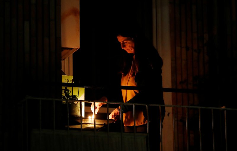 A woman lights a candle on her balcony in Rome March 19, 2020, as faithful across Italy say a prayer for people suffering from COVID-19. (CNS photo/Yara Nardi, Reuters)