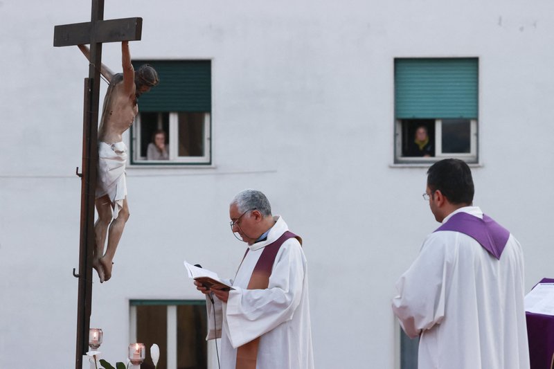 Two priests stand in front of a crucifix as they celebrate the Via Crucis (Way of the Cross) from the roof of their church, Santa Maria della Salute in Naples, Italy, March 20, 2020. (CNS photo/Ciro Napolipress, Fotogramma/IPA/ABACAPRESS.COMNo via Reuters)