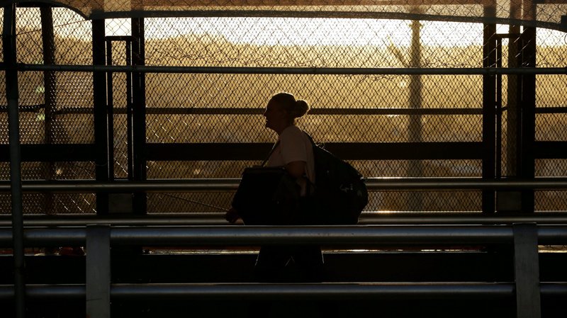 A woman near El Paso, Texas, walks on the international border bridge with Mexico March 13, 2020. The coronavirus pandemic has increased burdens on immigrants without legal status. (CNS photo/Jose Luis Gonzalez, Reuters)