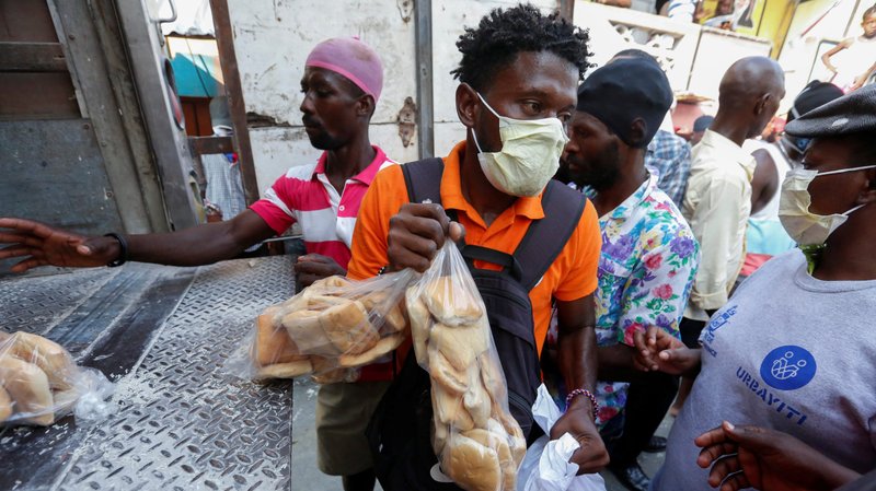 People take food distributed from a truck by a Haitian government program in Port-au-Prince, Haiti, April 6, 2020, amid the coronavirus (COVID-19) pandemic. The U.S. Conference of Catholic Bishops and other faith groups are urging the Trump administration to support debt relief for poor nations. (CNS photo/Jeanty Junior Augustin, Reuters)