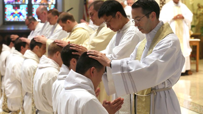 Clergymen lay their hands on men during their ordination Mass at St. Dominic's Church in Washington in 2014. Some dioceses are postponing priestly ordinations this year because of the coronavirus pandemic. (CNS photo/Bob Roller)
