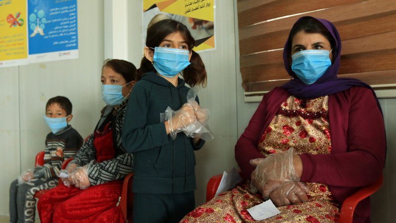 Displaced women and children wearing protective masks wait in the medical center of a camp in Dahuk, Iraq, March 7, 2020, during the COVID-19 pandemic. (CNS photo/Ari Jalal, Reuters)