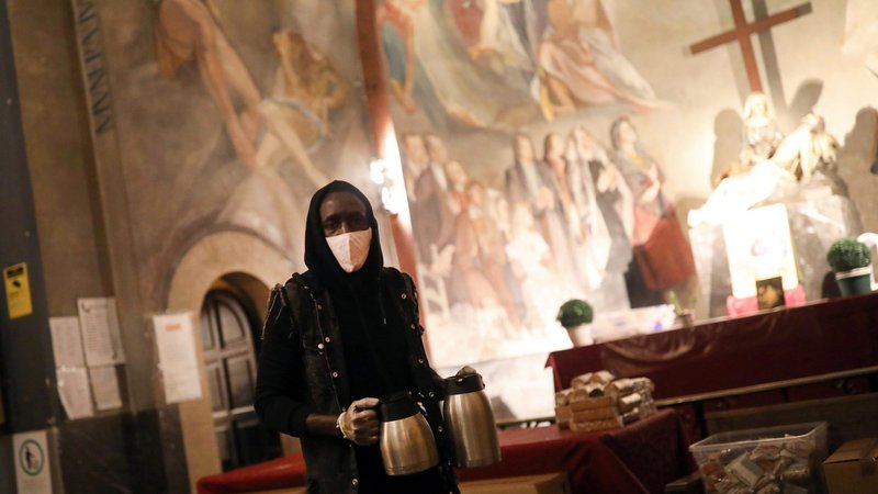 A volunteer carries coffee for people waiting for a free meal at the Church of Santa Anna in Barcelona, Spain, April 21, 2020, during the COVID-19 pandemic. (CNS photo/Nacho Doce, Reuters)