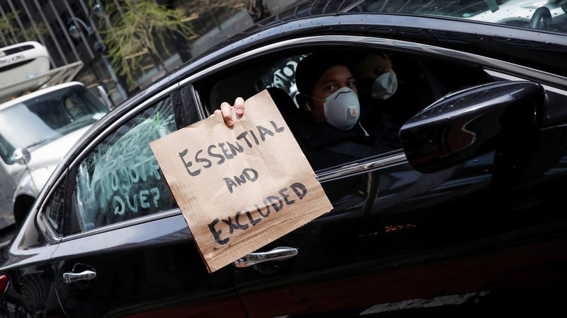 A worker in New York City holds a sign from a car during a caravan demonstration for the rights of essential immigrant workers April 21, 2020. (CNS photo/Mike Segar, Reuters)