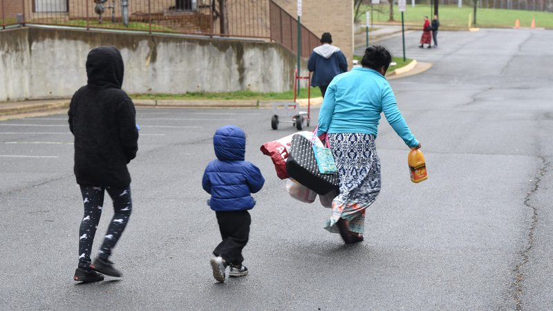 A Latino family in Falls Church, Va., walks away after receiving food at St. Anthony of Padua Church March 25, 2020. (CNS photo/Zoey Maraist, Arlington Herald)