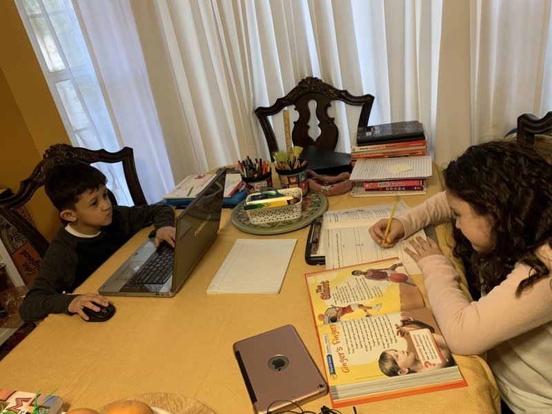 Riley (first grade) and Ruby (third grade), students at St. Andrew’s School in Pasadena, work on assignments at their home. (Photo courtesy of the Miller family)