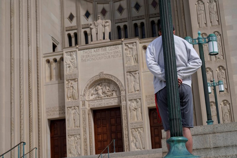 A man in Washington prays outside of the Basilica of the National Shrine of the Immaculate Conception on Palm Sunday April 5, 2020, during the coronavirus pandemic. (CNS photo/Joshua Roberts, Reuters)