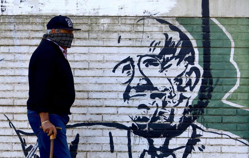 A man wearing a scarf as a protective measure against the coronavirus (COVID-19) walks past a mural depicting Pope Francis on Easter, April 12, in Buenos Aires, Argentina. (Catholic News Service/Matias Baglietto, Reuters)