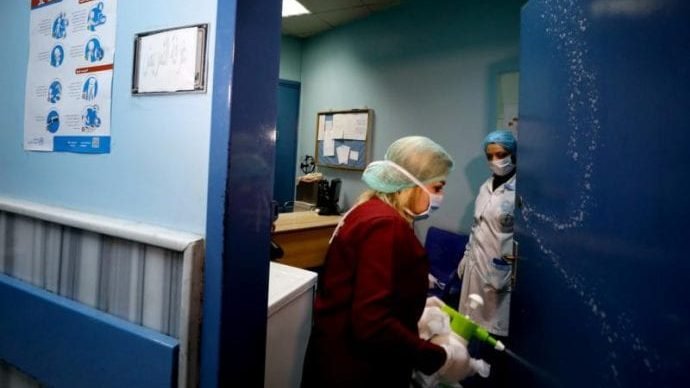 A worker sanitizes a door at a hospital to prevent the spread of COVID-19 in Damascus, Syria, March 19, 2020. (Omar Sanadiki/Reuters via CNS via Crux)