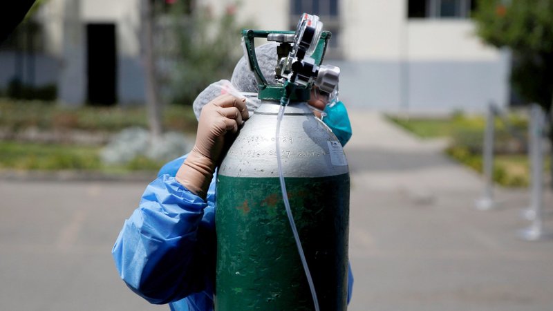A nurse adjusts an oxygen tank next to a tent for COVID-19 patients in the parking lot of a hospital in Lima, Peru, April 16, 2020. As coronavirus cases surge in Peru's two largest Amazonian cities, Iquitos and Pucallpa, Catholic leaders are struggling to find ways to provide the sick with the most basic health need, life-sustaining oxygen. (CNS photo/Sebastian Castaneda, Reuters)