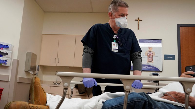 Chaplain Bill Simpson talks with a patient in the emergency room at SSM Health St. Anthony Hospital in Shawnee, Okla, April 23, 2020, amid the coronavirus pandemic. Officials at the Archdiocese of St. Paul and Minneapolis are assembling a team of priests to be trained for a ministry for patients sick with the coronavirus. (CNS photo/Nick Oxford, Reuters)