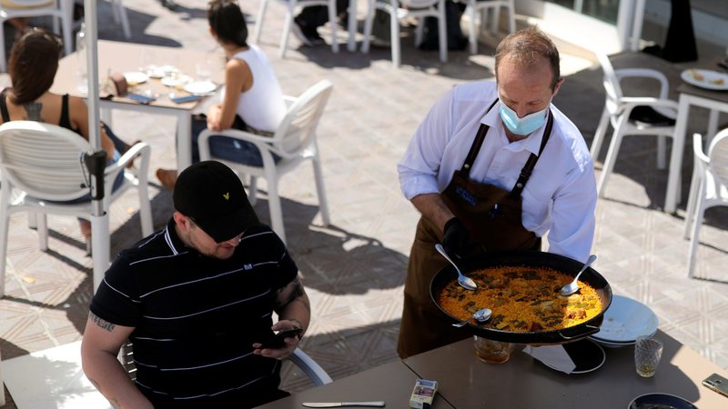A waiter wearing a protective mask serves a customer at an outdoor section of a restaurant in Valencia, Spain, May 18, 2020, during the COVID-19 pandemic. (CNS photo/Nacho Doce, Reuters)