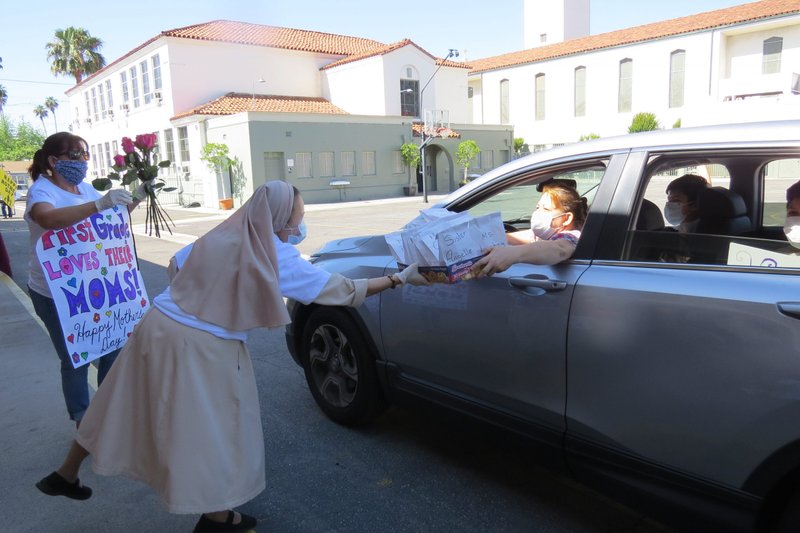 A teacher and a Daughter of the Divine Zeal sister hand out treats to mothers and students in a May 8 Mother’s Day celebration. (Courtesy St. Elisabeth School)